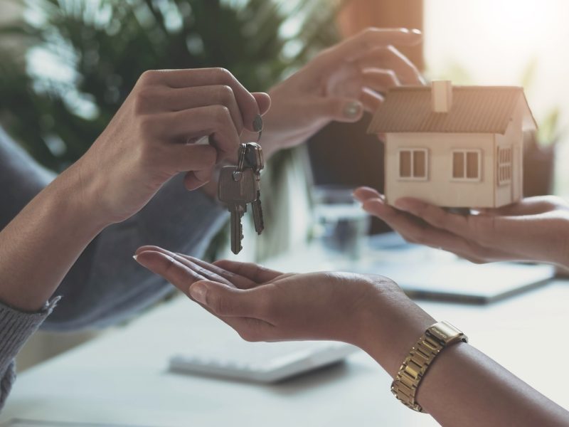 estate agent giving house keys to woman and sign agreement in office