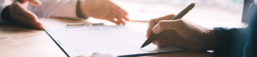 Real estate contract on desk with client signing in office.